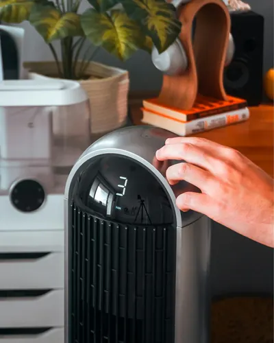 Hand adjusting the controls on a tower air purifier